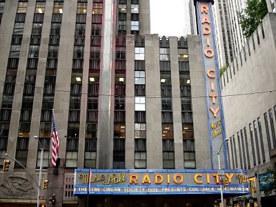 Click here to download a 1280 x 960 JPG image showing the buildings of downtown New York City towering above the Radio City Music Hall marquee.